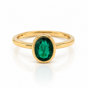 18ct yellow gold ring with a cetral bezel set oval emerald