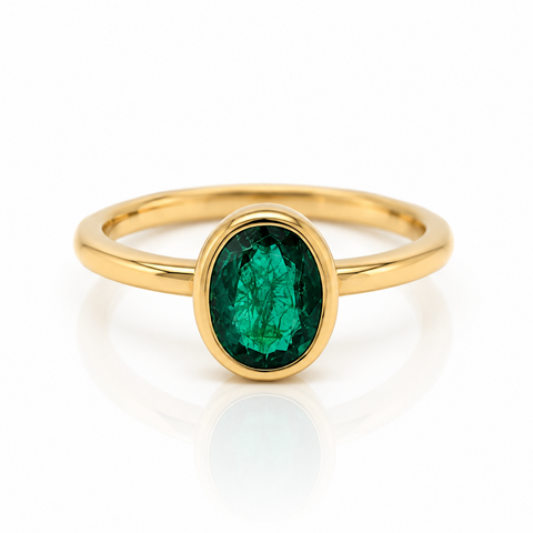 18ct yellow gold ring with a cetral bezel set oval emerald
