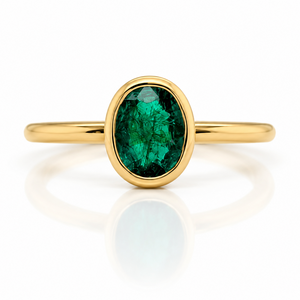 18ct yellow gold ring with a cetral bezel set oval emerald