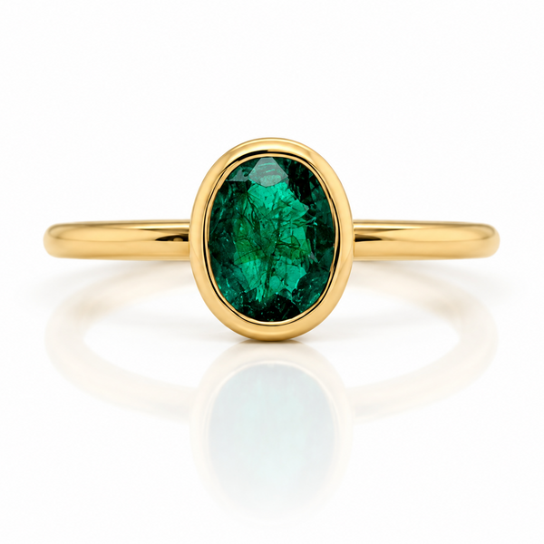 18ct yellow gold ring with a cetral bezel set oval emerald