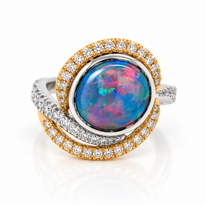 A luxury ring featuring a round iridescent opal center stone with blue, pink, and green flashes, surrounded by a double halo of gold and silver pavé-set diamonds on a white background.
