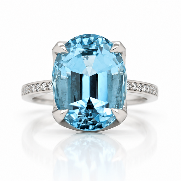 An oval-cut light blue Aquamarine ring in a platinum four-prong setting, featuring a diamond-paved band, shown on a clean white background with a soft reflection.