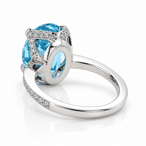 An oval-cut light blue Aquamarine ring in a platinum four-prong setting, featuring a diamond-paved band, shown on a clean white background with a soft reflection.